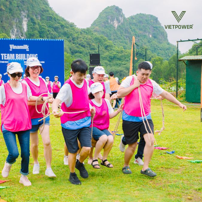 hình ảnh đội hồng đang cùng nhau vận chuyển đồng đội về đích trên một chiếc võng dây trong chương trình vinamilk team building 2024