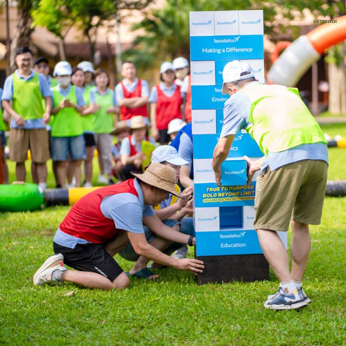 Đồng đội hỗ trợ nhau để xây nên ngọn tháp từ các khối gỗ thông điệp